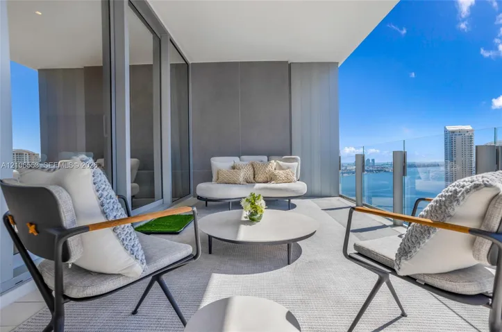 Covered balcony featuring expansive glass-panel railings, large-format tile flooring, and floor-to-ceiling sliding glass doors