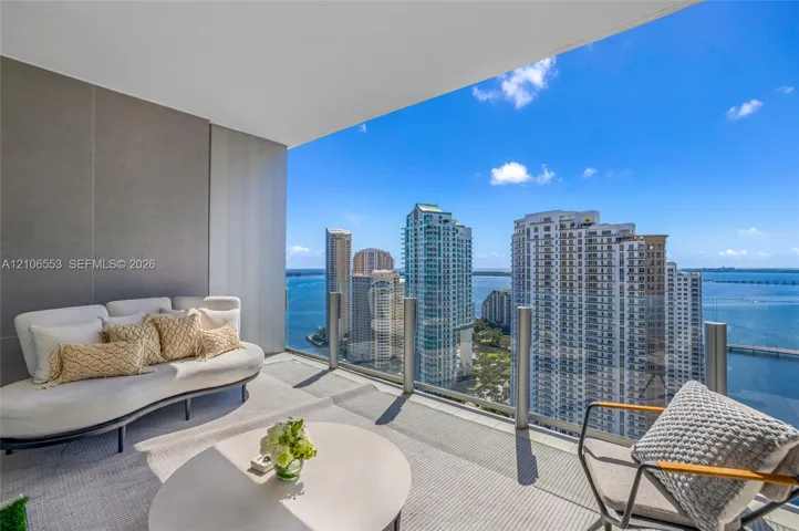 Covered balcony featuring glass railing and large-format tile flooring