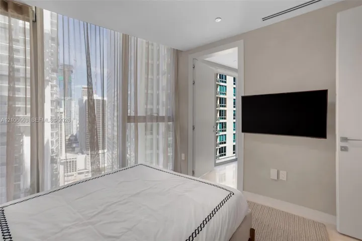Floor-to-ceiling windows, polished stone flooring, recessed ceiling lighting, and wall-mounted television hardware