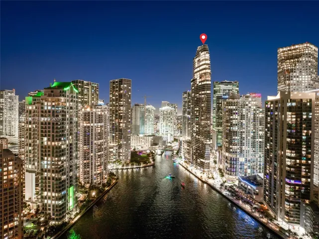 High-rise residential tower featuring a prominent cylindrical architectural design, floor-to-ceiling glass paneling, and proximity to a central waterway
