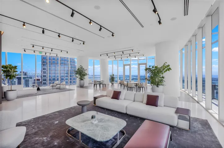 Expansive interior space featuring floor-to-ceiling windows, polished stone flooring, and adjustable overhead track lighting