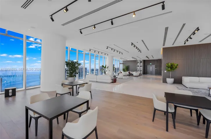 Open-concept space featuring floor-to-ceiling windows, wood-finish flooring, polished stone tile flooring, and integrated track lighting