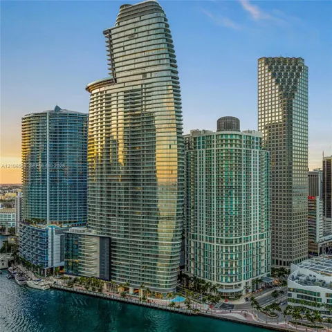 High-rise residential tower featuring a glass-curtain facade, wrap-around balconies, and waterfront positioning