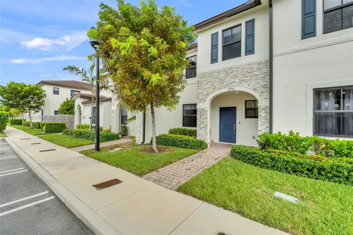 Stucco exterior featuring stacked stone veneer detailing, arched entryway, paved walkway, and dark-toned shutters