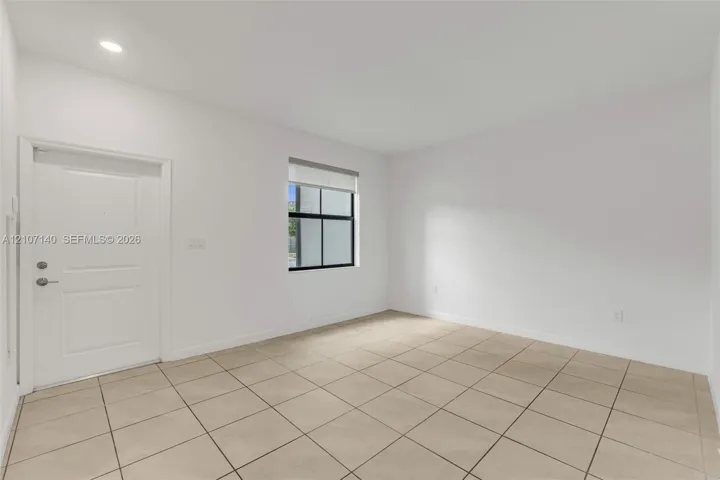 Neutral-toned ceramic tile flooring, recessed ceiling lighting, and a single-panel interior door
