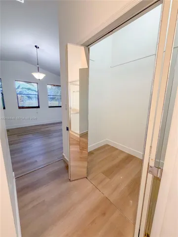 Wood-finish flooring, vaulted ceiling, built-in mirror-paneled closet door, and pendant lighting