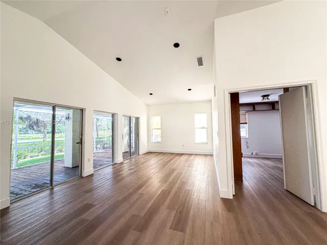 Vaulted ceilings, wood-finish flooring, recessed lighting, and expansive glass sliding doors