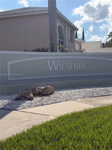 Stucco community monument sign featuring dimensional lettering, decorative stone accents, and manicured turf