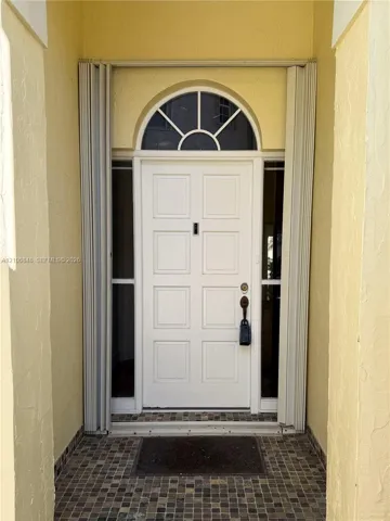 Entryway featuring a white eight-panel door, arched transom window, dual vertical sidelights, and a mosaic tile threshold