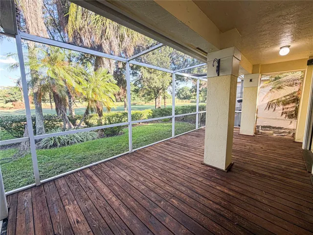 Screened lanai featuring wood-finish decking, structural support columns, and overhead lighting