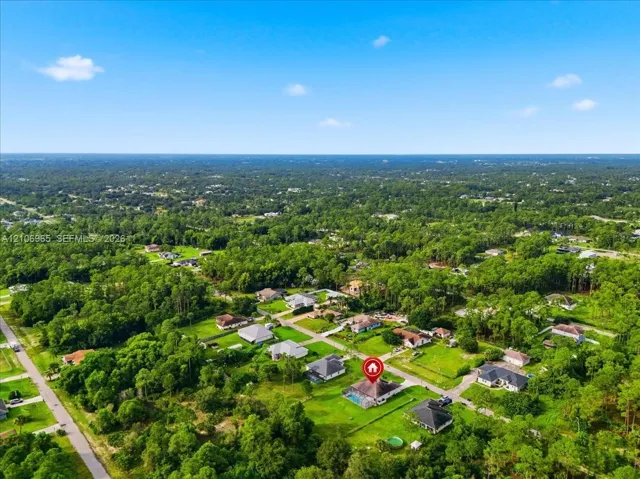 Aerial perspective of a residential property featuring an in-ground swimming pool, screened-in lanai, and substantial yard space situated within a forested landscape