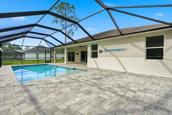 Screened-in lanai featuring a swimming pool, concrete paver decking, and a stucco exterior finish