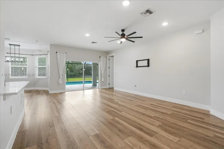 Open-concept living space featuring wood-finish flooring, recessed lighting, a modern ceiling fan, and sliding glass doors with access to an outdoor pool area