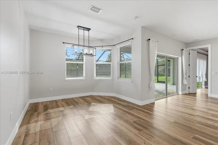 Dining area featuring wood-finish flooring, a multi-light metal chandelier, a bay window configuration, and sliding glass doors