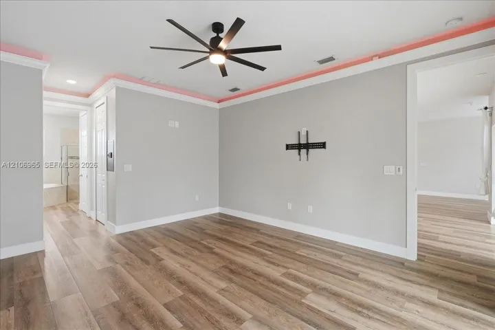 Living space featuring wood-finish flooring, recessed ceiling lighting, crown molding with accent lighting, and a multi-blade ceiling fan
