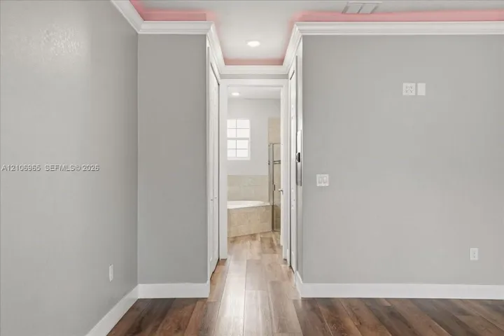 Wood-finish flooring, recessed ceiling lighting, crown molding, and neutral interior wall paint