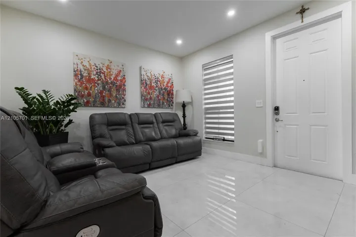 Large-format tile flooring, recessed ceiling lighting, and a multi-panel exterior door with smart lock hardware