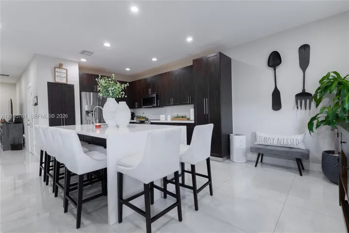 Kitchen featuring dark wood cabinetry, a center island with a white countertop, recessed lighting, and large-format tile flooring