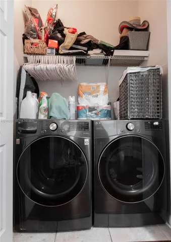 Laundry closet featuring side-by-side charcoal-finish front-load washer and dryer with wire shelving