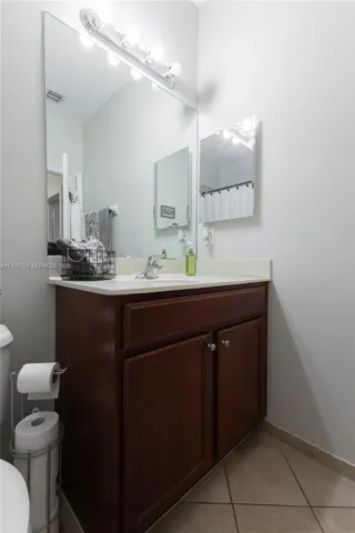 Wood-finish vanity cabinet, solid-surface countertop, full-width mirror, and multi-bulb light fixture