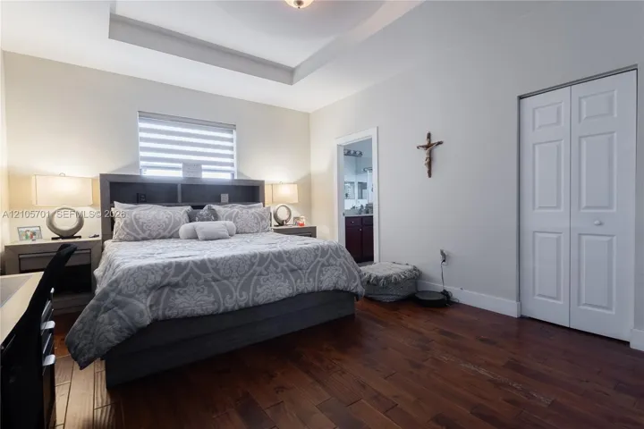 Room featuring tray ceilings, wood-finish flooring, and dual-panel closet doors