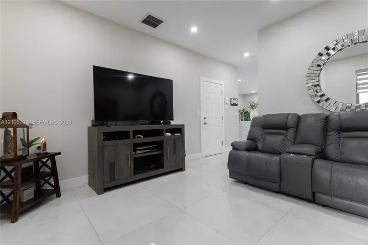 Neutral interior featuring polished large-format tile flooring, recessed ceiling lighting, and a six-panel interior door
