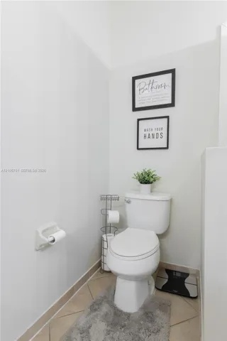 White porcelain toilet with a recessed wall-mounted paper holder and tile flooring