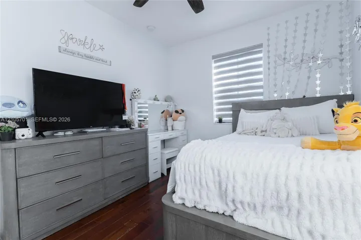 Room featuring wood-finish flooring, a ceiling fan, and horizontal window shades