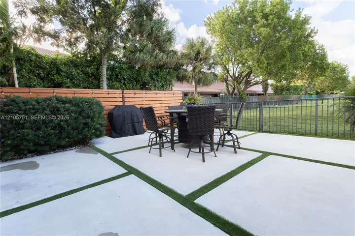 Backyard featuring a concrete paver patio with turf inlays, horizontal wood privacy fencing, and metal perimeter fencing