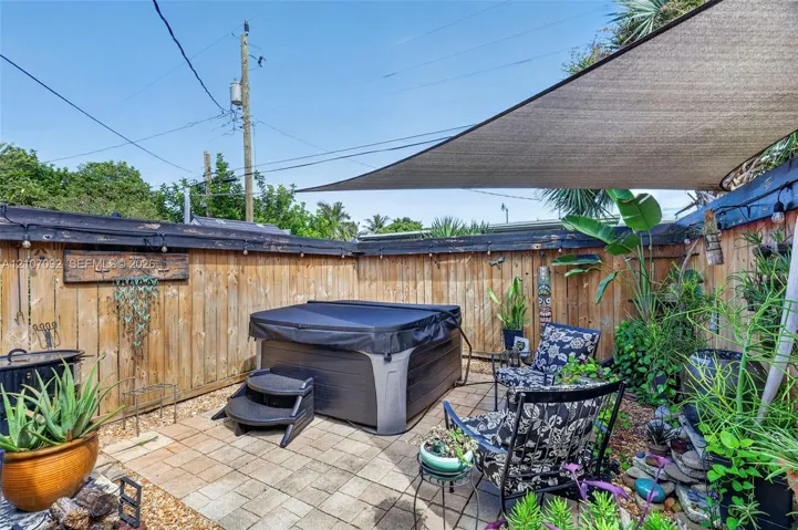 Private outdoor space featuring hardscape stone pavers, a perimeter wood privacy fence, and an overhead shade sail