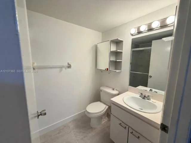 Bathroom featuring a vanity with integrated sink, wall-mounted medicine cabinet with open shelving, tile flooring, and a multi-bulb light fixture above the mirror