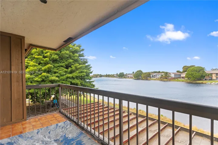 Covered balcony featuring tile flooring and metal railings overlooking a waterfront