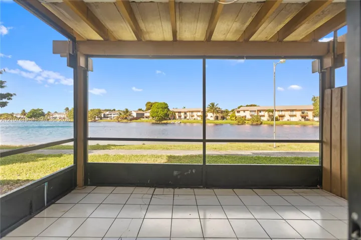 Screened-in patio featuring a tile floor, exposed beam ceiling, and direct water frontage