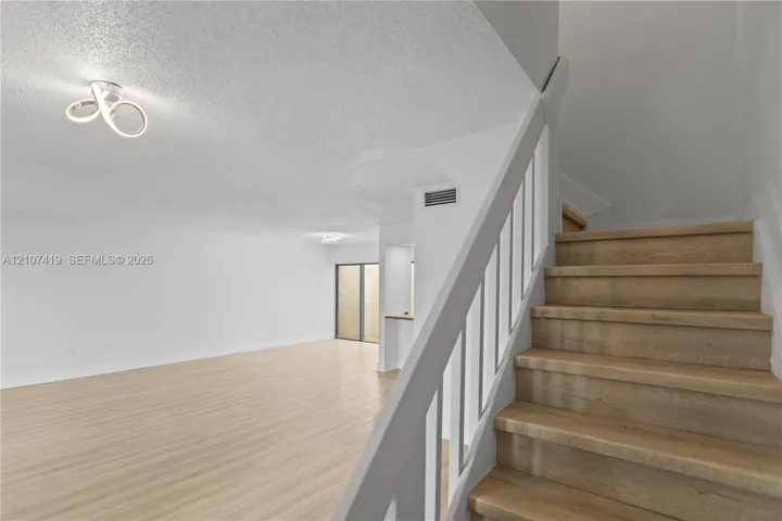 Interior featuring wood-finish flooring, staircase with a white railing, and modern geometric flush-mount lighting