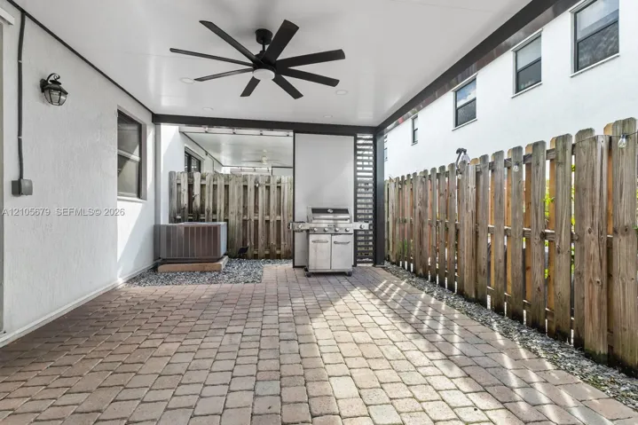 Covered patio featuring paver flooring, multi-blade ceiling fan, recessed lighting, and wood privacy fencing