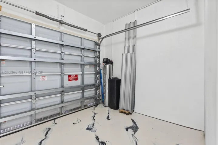 Finished garage interior featuring a metal sectional door, epoxy-coated floor with decorative marbling, and an integrated water filtration system