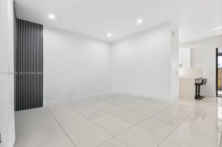 Large-format tile flooring, vertical slat accent wall, and recessed lighting