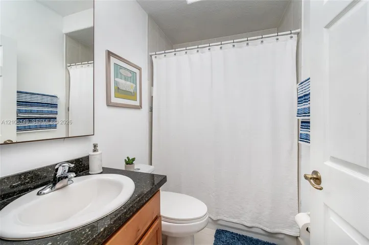 Bathroom featuring a vanity with a stone-finish countertop, integrated oval basin, and single-handle chrome faucet