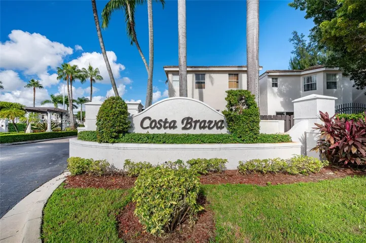 Stucco monument sign featuring professional lettering, landscaped shrubbery, mature palm trees, and manicured turf