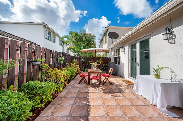 Stucco exterior featuring a tiled patio, wood-slat privacy fencing, and exterior wall-mounted lighting