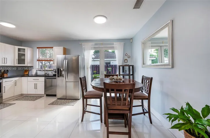 Kitchen featuring white cabinetry, stainless steel appliances, large-format tile flooring, and glass French doors