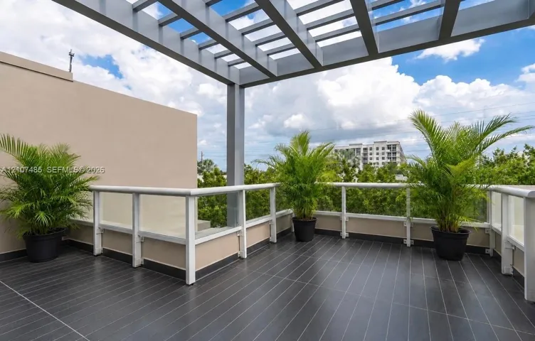 Terrace featuring dark tile flooring, a metal pergola, and glass panel railing