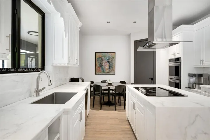 Kitchen featuring white cabinetry, stone countertops, stainless steel undermount sink, built-in double wall oven, and wood-finish flooring