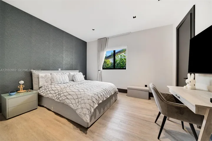 Textured charcoal accent wall featuring recessed ceiling lighting, light wood-finish flooring, and black window trim