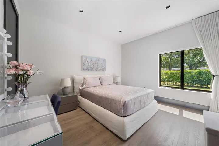 High-ceiling bedroom featuring wood-finish flooring, recessed lighting, and a large black-framed window