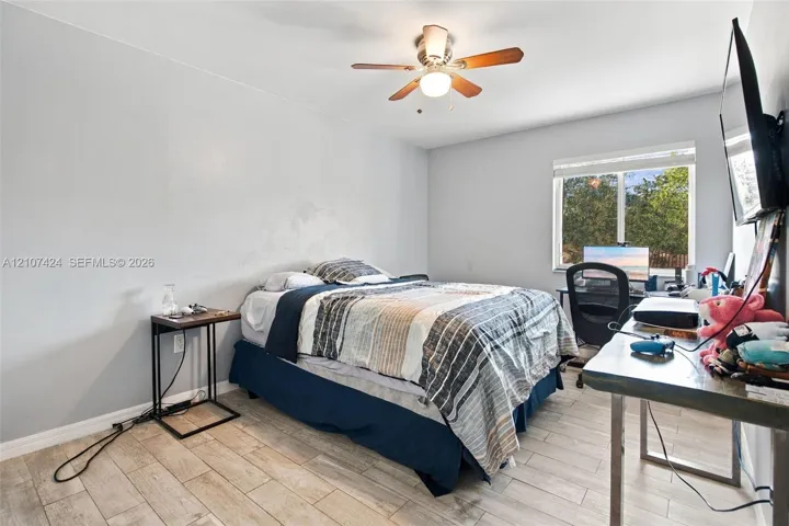 Room featuring wood-finish tile flooring, ceiling fan with light fixture, and single-pane window