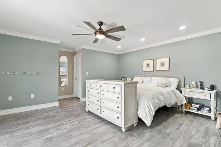 Oversized bedroom featuring recessed lighting, crown molding, wood-finish tile flooring, and a multi-blade ceiling fan