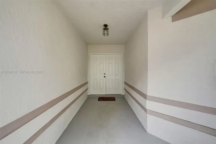 Covered entryway featuring double entry doors, textured wall finishes, and overhead lantern-style lighting