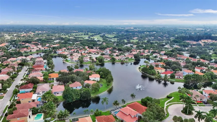 Aerial perspective featuring a community lake, central fountain, paved street network, and mature landscaping