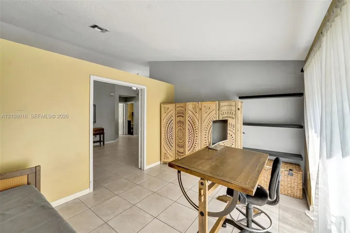 Room featuring tile flooring, vaulted ceilings, and wall-mounted shelving